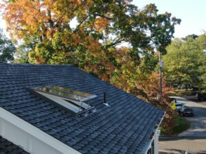 House roof with skylight, autumn trees view.