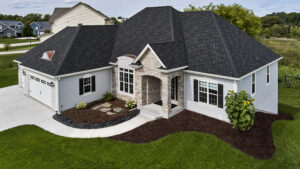 Suburban house with gray siding and dark roof.