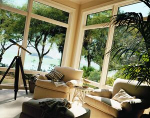 Cozy sunroom overlooking beach through large windows.