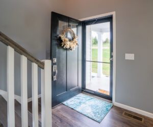 Open front door with wreath and welcome mat.