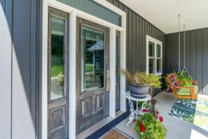 Modern porch with swing, plants, and glass doors.