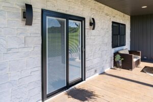 Modern patio with sliding glass door and stone wall.