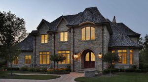 Luxury stone house with illuminated windows at dusk.