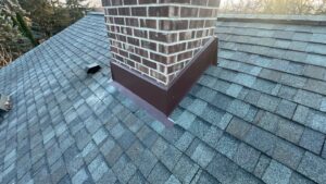 Brick chimney with flashing on shingled roof.