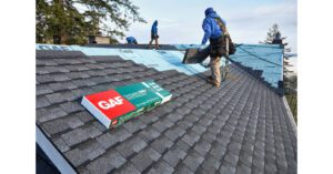 Workers installing GAF shingles on a roof.