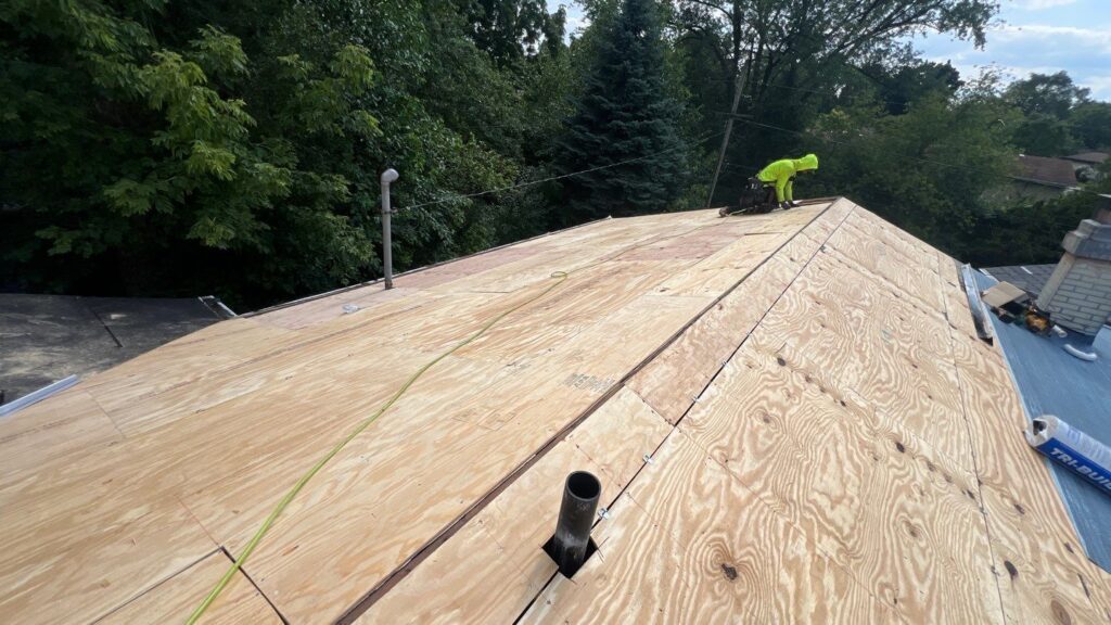Worker installing plywood roof decking
