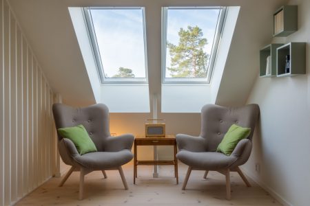 Cozy attic lounge with chairs under skylights.
