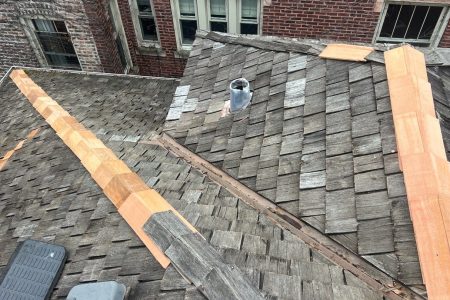 Wooden roof with repaired shingles and vent pipe