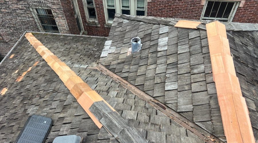 Wooden roof with repaired shingles and vent pipe