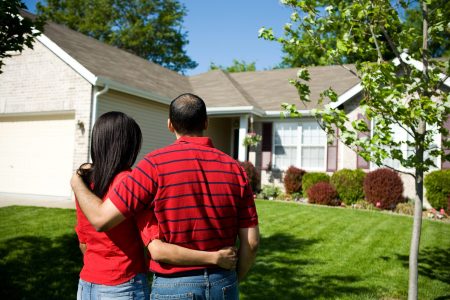 Couple embracing in front of their house.