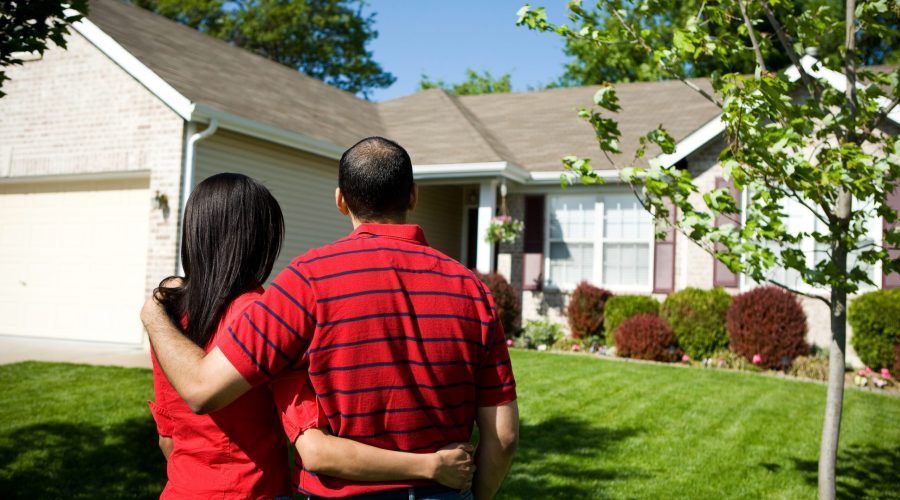 Couple embracing in front of their house.