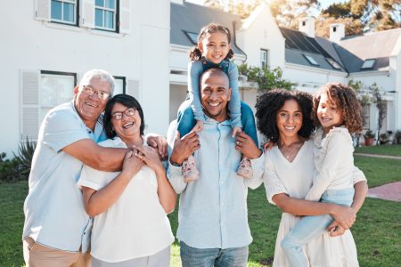Multigenerational family smiling outside suburban home