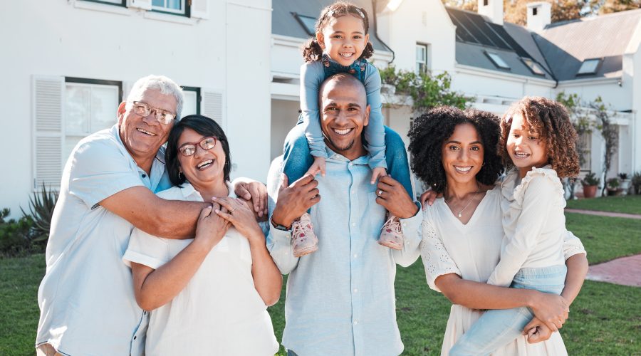 Multigenerational family smiling outside suburban home