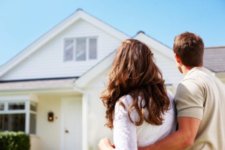 Couple admiring white suburban house.