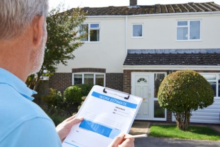 man-looking-at-house-holding-work-estimate-sheet