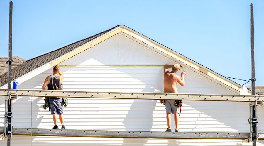Two workers measuring a house facade