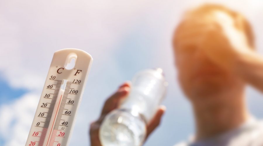 Person holding water bottle near hot thermometer.