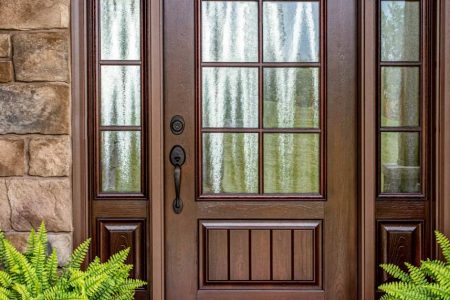 Wooden front door with welcome mat and plants