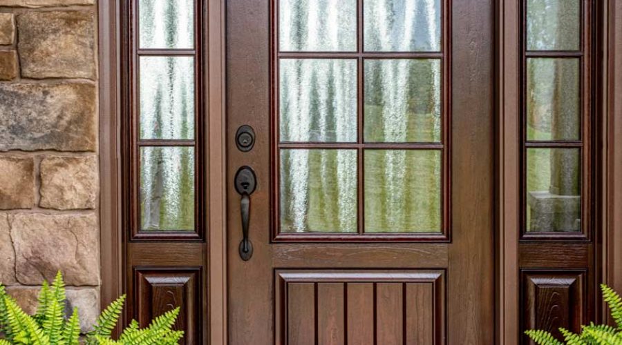Wooden front door with welcome mat and plants