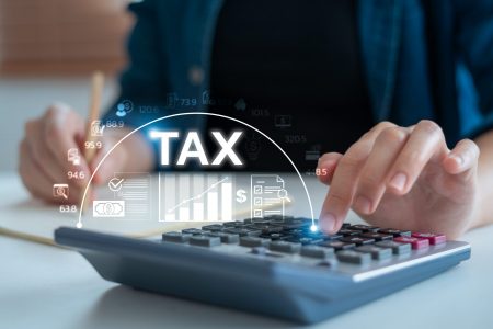 Person calculating taxes with calculator and documents