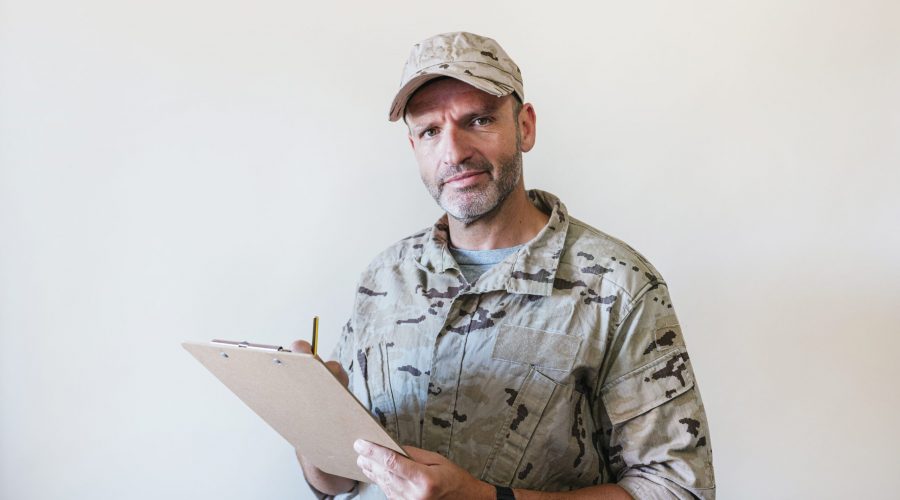Military person with clipboard in desert uniform.